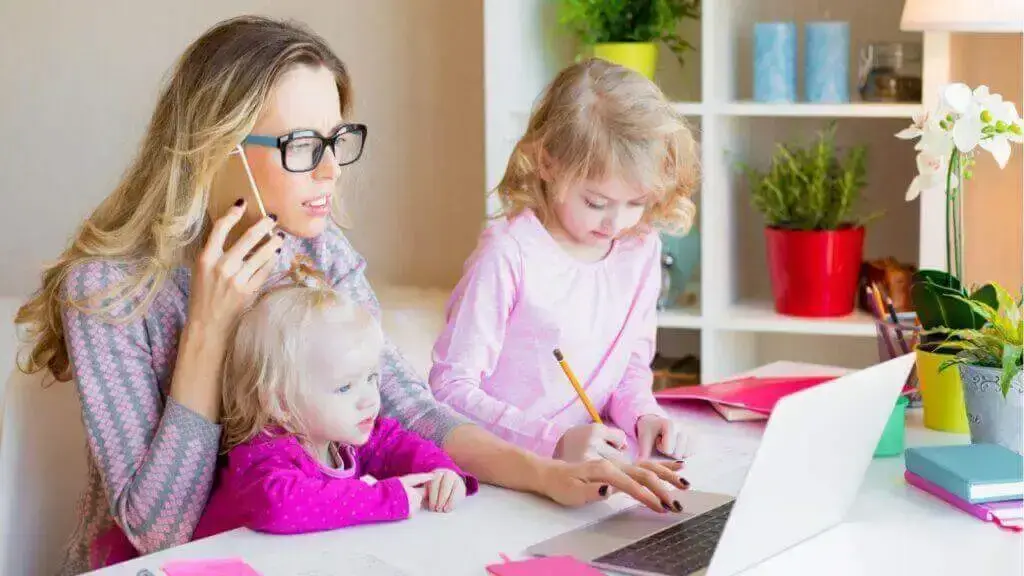 a woman and two children working on a laptop